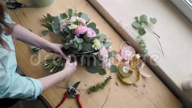 女花匠在<strong>鲜花店</strong>制作美丽的花束，为婚礼准备佩恩和玫瑰花组合